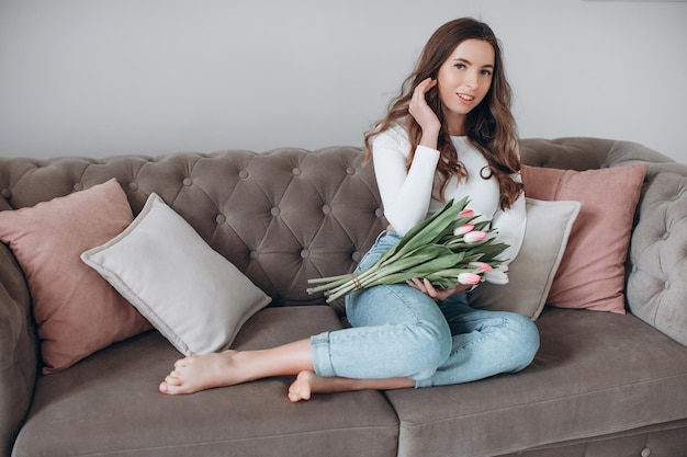 Gelukkige jonge vrouw die lacht en een boeket tulpen vasthoudt tijdens het vieren van Vrouwendag