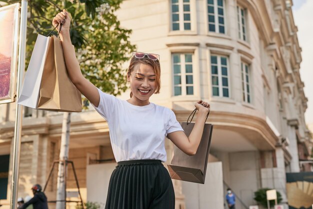 Gelukkige jonge vrouw die na het winkelen bij de uitverkoop van het winkelcentrum loopt