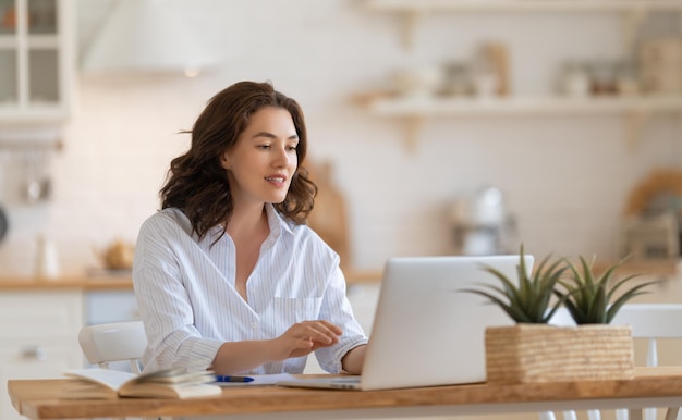 Gelukkige jonge vrouw die online werkt en kijkt naar webinar-podcast op laptop