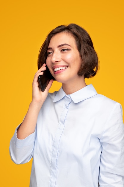 Gelukkige jonge vrouw die op smartphone spreekt