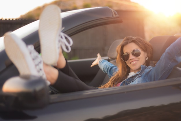 Gelukkige jonge vrouw die van haar convertibele auto geniet