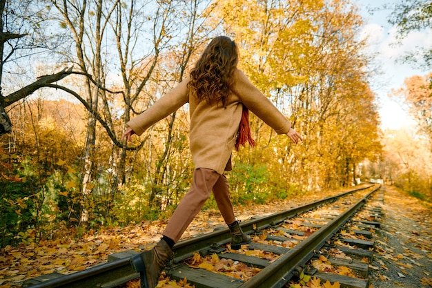 Gelukkige jonge vrouw geniet van herfstbladeren vallen