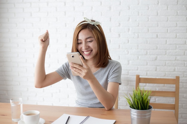 Foto gelukkige jonge vrouw houdt de telefoon vast in café