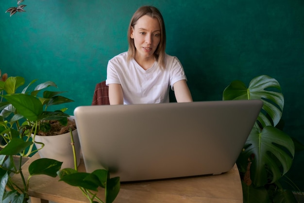 Foto gelukkige jonge vrouw in jeans en witte t-shirt thuis aan tafel zonnige dag