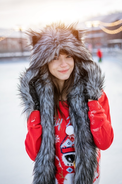 Gelukkige jonge vrouw in wolfshoed in de winter op de ijsbaan