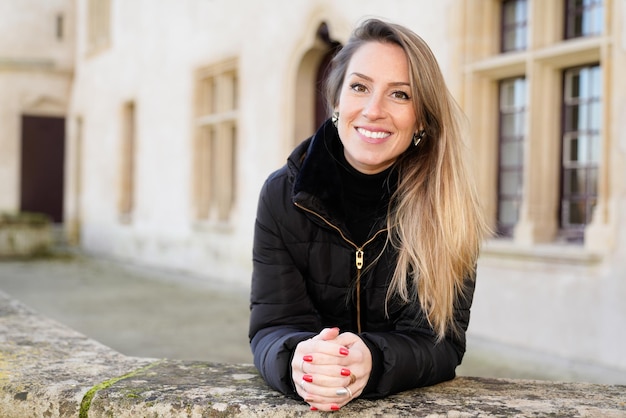 Foto gelukkige jonge vrouw met blonde lange haren toeristische poseren rond oude straten