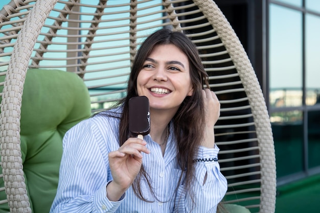 Gelukkige jonge vrouw met chocolade-ijs in een hangmat