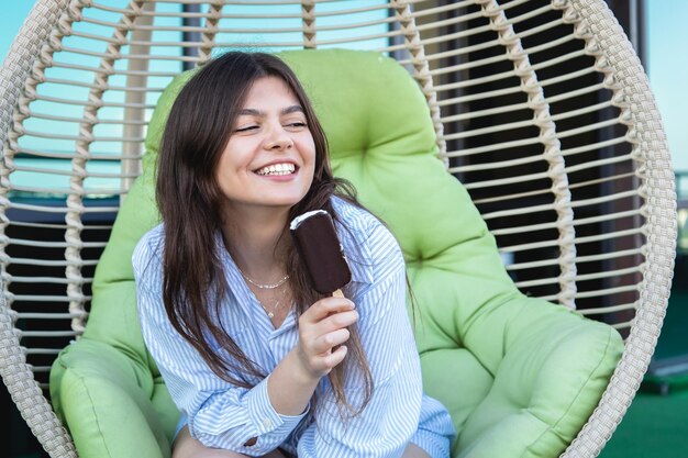 Gelukkige jonge vrouw met chocolade-ijs in een hangmat