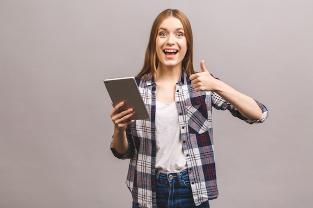 Gelukkige jonge vrouw met digitale tablet die duim toont.