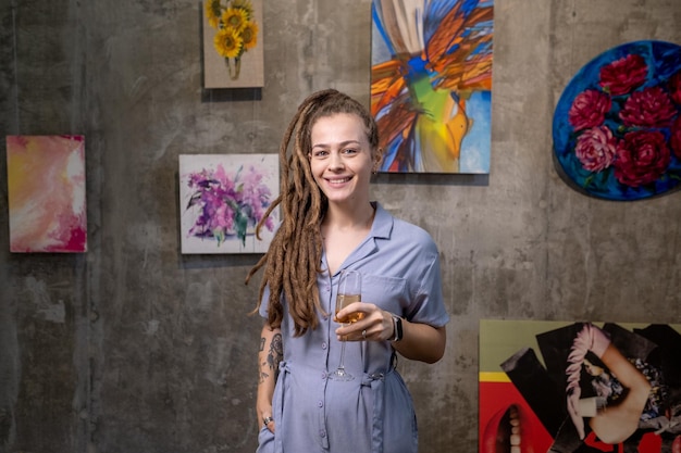 Gelukkige jonge vrouw met dreadlocks roosteren met fluit champagne