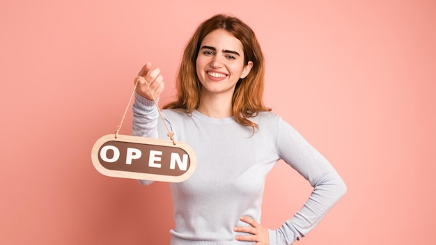 Gelukkige jonge vrouw met een open bord in een roze studio.