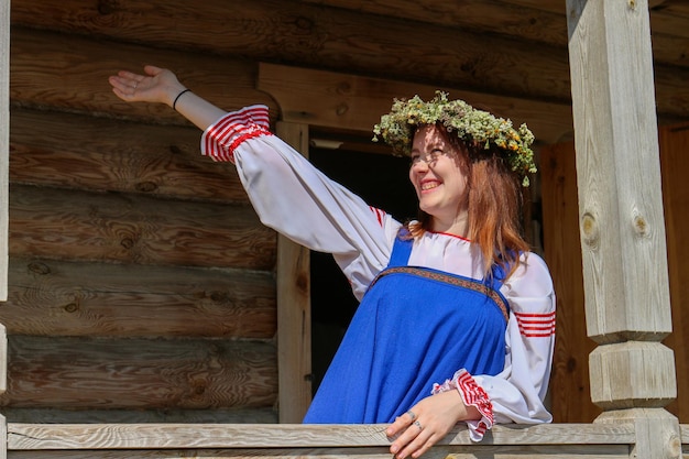 Foto gelukkige jonge vrouw met opgeheven arm die bij de reling van het huis staat