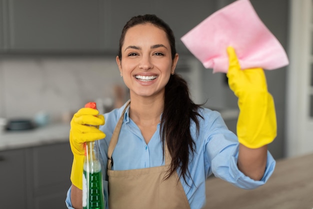 Gelukkige jonge vrouw met schoonmaakspray en doek