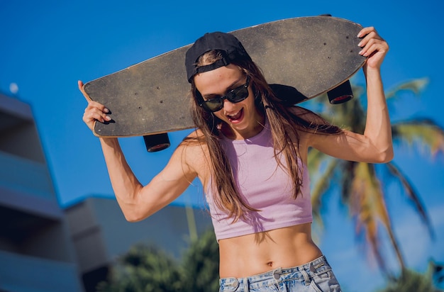 Gelukkige jonge vrouw met skateboard geniet van longboarden in het skatepark