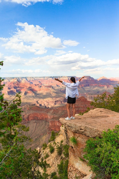 Gelukkige jonge vrouw op een steile klif die geniet van het prachtige uitzicht over de beroemde Grand Canyon bij zonsondergang Grand Canyon National Park Arizona USA