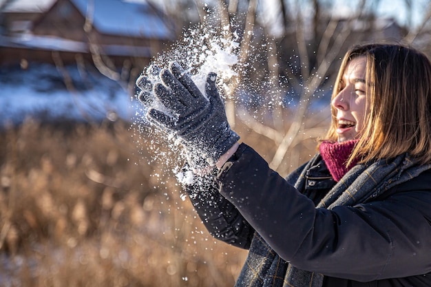 Gelukkige jonge vrouw op een wandeling in de winter met sneeuw in haar handen