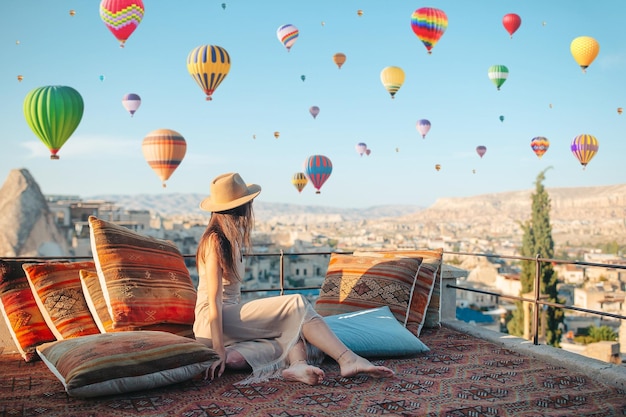 Gelukkige jonge vrouw tijdens zonsopgang kijken naar heteluchtballonnen in Cappadocië, turkije