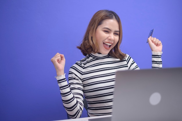 Gelukkige jonge vrouw winkelt online via laptop, met creditcard