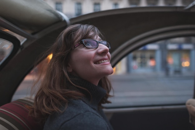 Gelukkige jonge vrouw zit in een vintage auto.