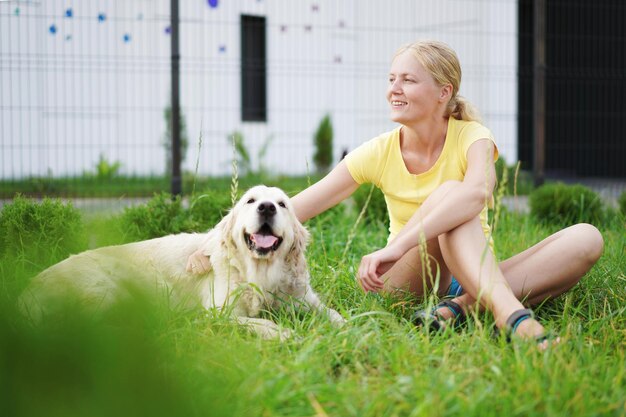 Gelukkige jonge vrouw zit met een labrador retriever op een grasveld