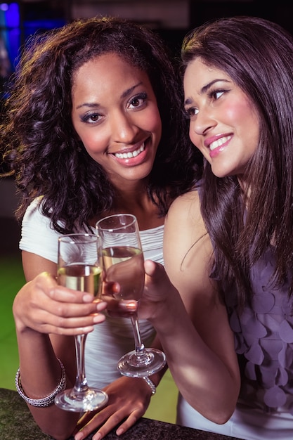 Gelukkige jonge vrouwen die champagne in bar hebben