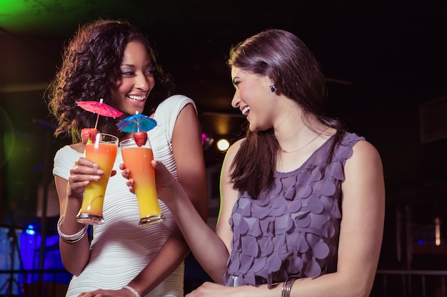 Gelukkige jonge vrouwen die cocktail in bar hebben