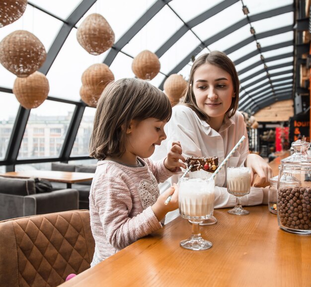 Gelukkige jonge vrouwenmoeder met kinderen die een milkshake drinken