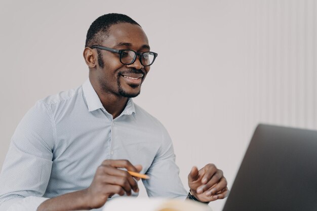 Gelukkige jonge zakenman in formele kleding heeft videochat met klant of collega's in zoom