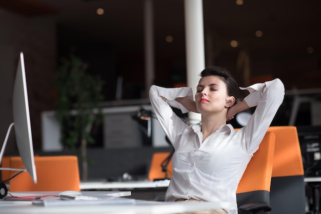 gelukkige jonge zakenvrouw die ontspant en inspiratie opdoet tijdens het werken op een desktopcomputer bij een modern, helder starup-kantoorinterieur