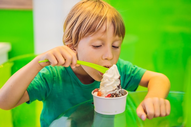 Gelukkige jongen die een lekker ijsje of bevroren yoghurt eet