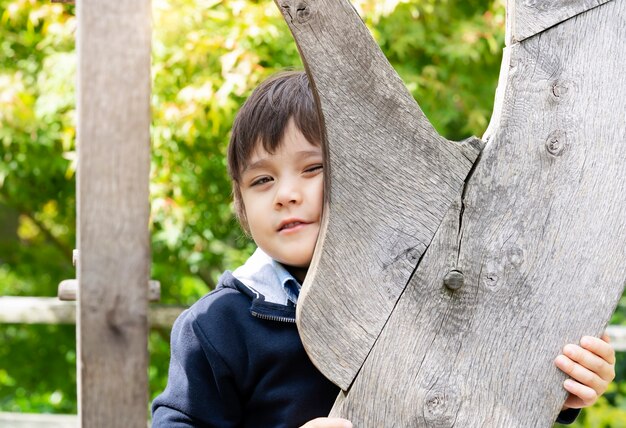 Gelukkige jongen die grappig gezicht maakt terwijl het spelen van huid - en - zoekt bij het park,