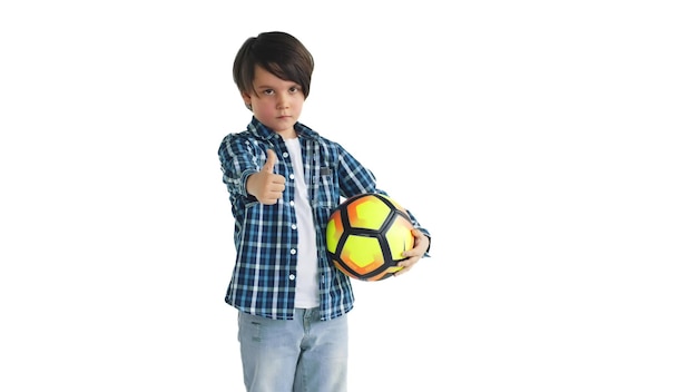 Gelukkige jongen die voetbal houdt en glimlachend gebarend goedkeuringsteken geïsoleerd op een witte achtergrond