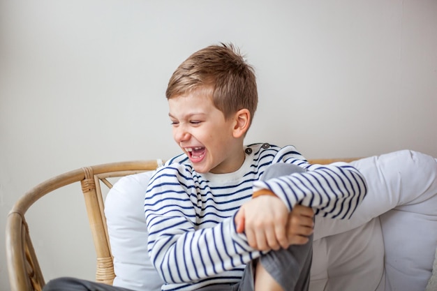 Gelukkige jongen die wegkijkt terwijl hij thuis op de bank zit