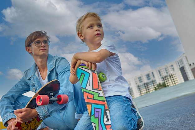 Foto gelukkige jongen en zijn oudere broer rijden buiten op het skateboard