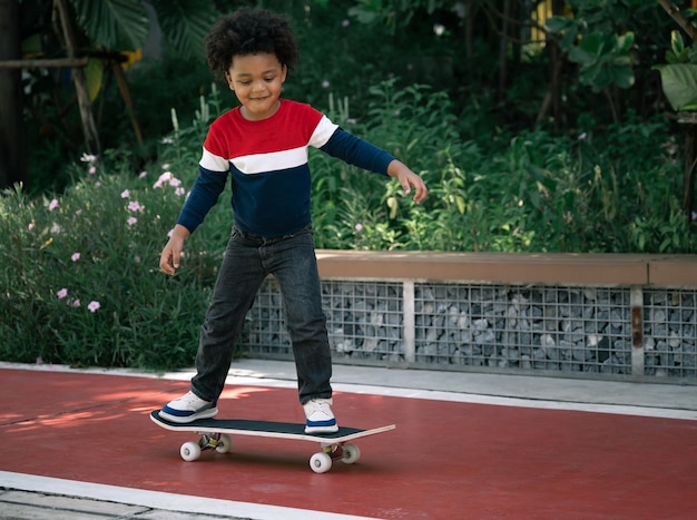 Gelukkige jongen jongen met afro haar en skateboard in het park