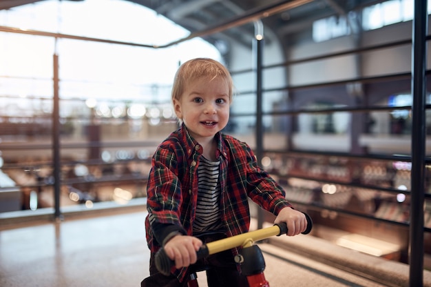 Gelukkige jongen op een loopfiets in het winkelcomplex