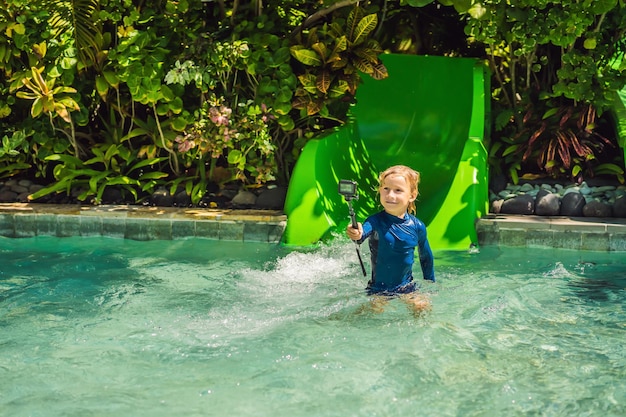 Gelukkige jongen op waterglijbaan in een zwembad die plezier heeft tijdens de zomervakantie in een mooie