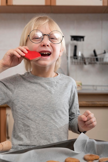 Gelukkige jongen proeft versgebakken koekjes Kind in de keuken bereidt koekjes