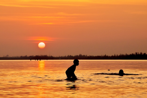 Gelukkige jongen spelen op het strand bij zonsondergang