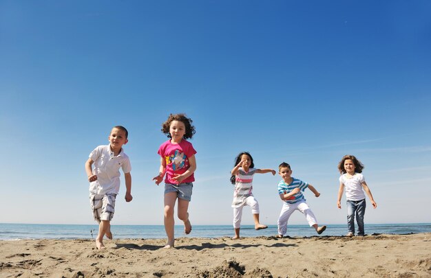 gelukkige jongerengroep veel plezier rennen en springen op het strand prachtig zandstrand