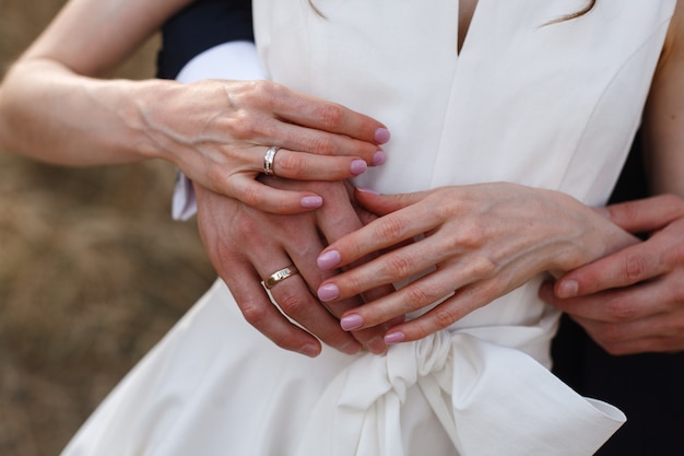 gelukkige jonggehuwden hand in hand en omhelzen zachtjes van dichtbij. Trouwdag. schattig net getrouwd stel. verliefde paar knuffels op romantische date. romantisch moment van dichtbij. bruid en bruidegom genieten van elkaar