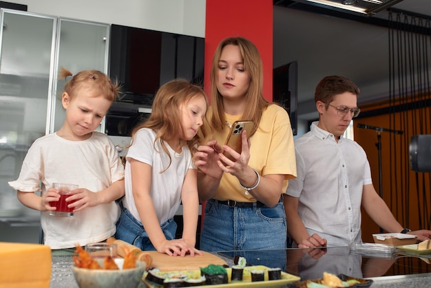 Gelukkige kaukasische familie die plezier heeft en thuis sushi en broodjes eet in de keuken