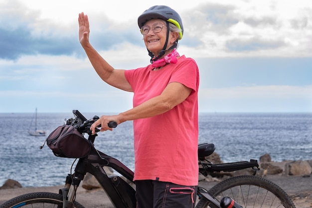 Gelukkige Kaukasische fietser senior vrouw in roze loopt langs de zee in de zomervakantie