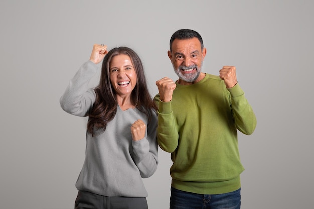 Gelukkige kaukasische oude man en vrouw die overwinning vieren en een succesgebaar maken