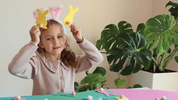 Foto gelukkige kind meisje in konijn ooren maken en spelen paaspapier gekleurde krans paaskonijn kinderen