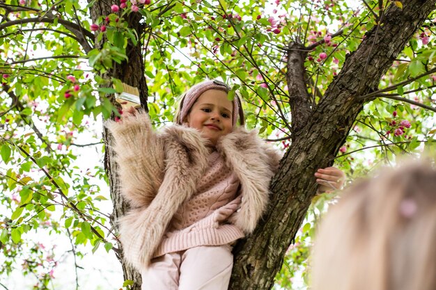 Gelukkige kind speelt in de tuin klimt op de boom