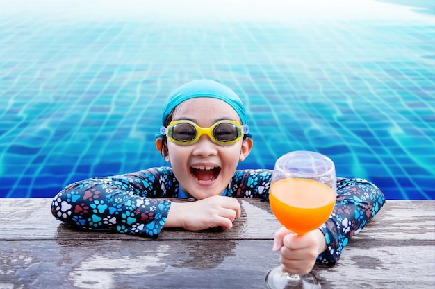 Gelukkige kinderen aan de kant van het zwembad, meisje ontspannen met drankje van de zomer