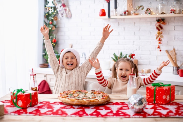 gelukkige kinderen broer en zus pizza eten in de keuken