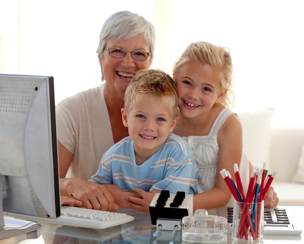 Gelukkige kinderen die een computer gebruiken met hun grootmoeder
