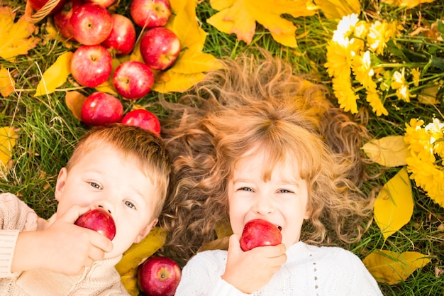 Gelukkige kinderen die op herfstbladeren liggen Grappige kinderen buiten in het herfstpark